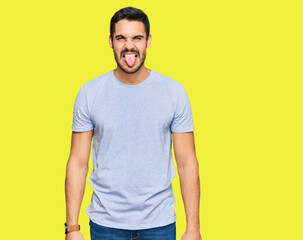 Obraz premium Young hispanic man wearing casual clothes sticking tongue out happy with funny expression. emotion concept.