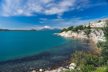 Fototapeta premium Rocky seashore with clear water and sunny weather. Beautiful nature of Norway. Picturesque Scandinavian landscape. Lofoten islands, Europe stock photo