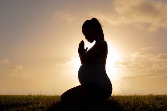 A pregnant woman praying outside. Peace of mind in nature.