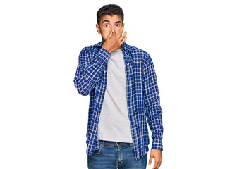 Fototapeta premium Young handsome african american man wearing casual clothes smelling something stinky and disgusting, intolerable smell, holding breath with fingers on nose. bad smell