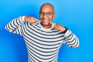 Middle age latin man wearing casual clothes and glasses smiling cheerful showing and pointing with fingers teeth and mouth. dental health concept.