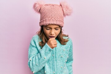 Little beautiful girl wearing wool sweater and cute winter hat feeling unwell and coughing as...