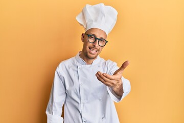 Bald man with beard wearing professional cook uniform smiling friendly offering handshake as greeting and welcoming. successful business.