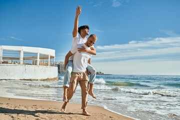 Lovely gay couple on piggyback ride at the beach.
