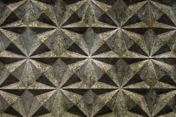 Background, wall of gray blocks with triangular patterns and shadows of the sun