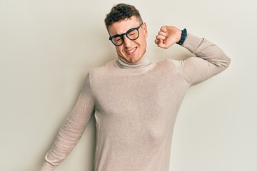 Hispanic young man wearing casual turtleneck sweater stretching back, tired and relaxed, sleepy and yawning for early morning