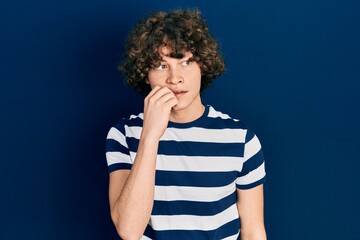 Fototapeta na wymiar Handsome young man wearing casual striped t shirt looking stressed and nervous with hands on mouth biting nails. anxiety problem.