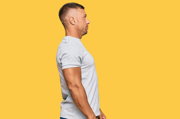 Handsome muscle man wearing casual grey tshirt looking to side, relax profile pose with natural face with confident smile.