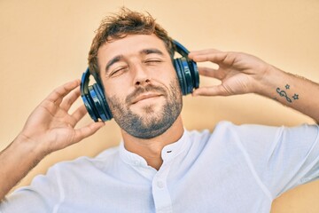 Handsome man with beard wearing headphones and enjoying listening to music outdoors