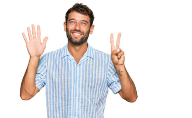 Naklejka premium Handsome young man with beard wearing casual fresh shirt showing and pointing up with fingers number seven while smiling confident and happy.