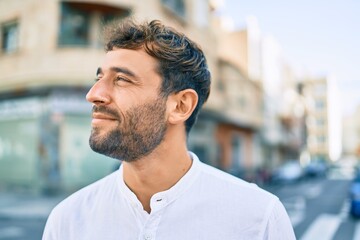 Handsome man with beard wearing casual white shirt on a sunny day smiling happy outdoors