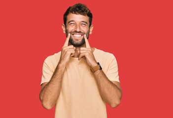 Obraz premium Handsome young man with beard wearing casual tshirt smiling with open mouth, fingers pointing and forcing cheerful smile