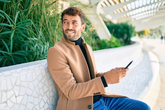 Handsome business man wearing elegant jacket using smartphone smiling happy outdoors