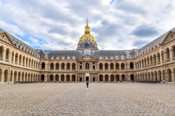 Obraz premium Musee de l'Armee, Hotel National des Invalides with a woman walking in, in Paris, isometric front view with blue sky and lots of clouds with multiple color tones