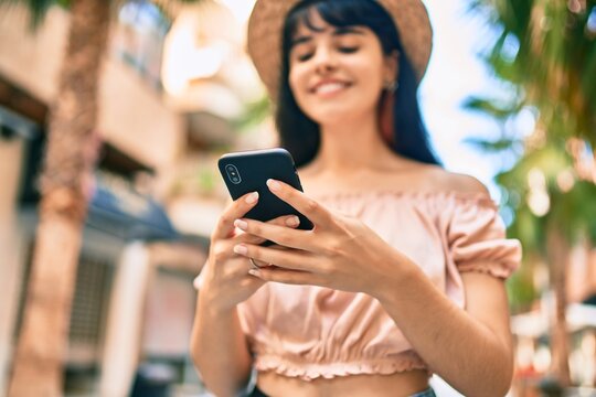 Young hispanic tourist girl wearing summer style using smartphone at the city.