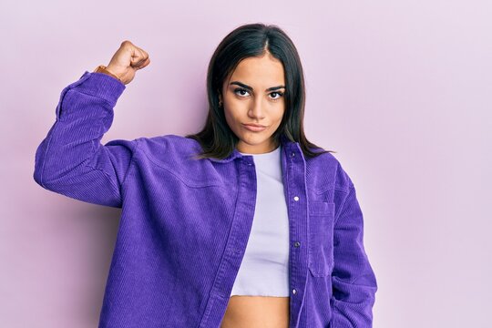 Young brunette woman wearing casual clothes strong person showing arm muscle, confident and proud of power