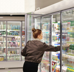 Woman choosing frozen food from a supermarket freezer