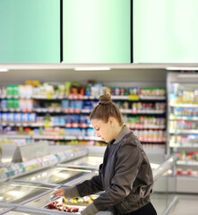 Woman choosing frozen food from a supermarket freezer