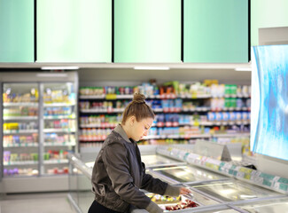 Woman choosing frozen food from a supermarket freezer