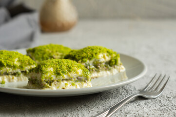 Traditional turkish new dessert cold milky baklava with pistachio on white rustic table,  ramadan or holiday desserts concept