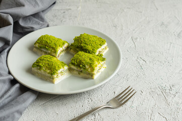 Traditional turkish new dessert cold milky baklava with pistachio on white rustic table,  ramadan or holiday desserts concept