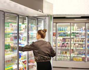Woman choosing frozen food from a supermarket freezer