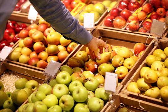 man buying pears and apples in a supermarket