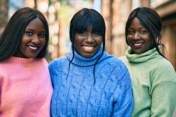 Three african american friends smiling happy hugging at the city.