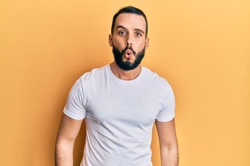 Young man with beard wearing casual white t shirt scared and amazed with open mouth for surprise, disbelief face