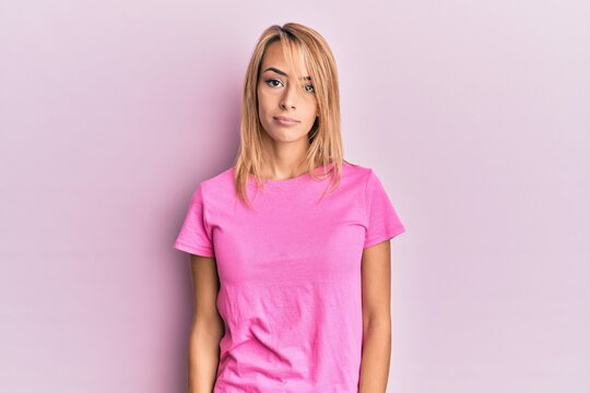 Beautiful blonde woman wearing casual pink tshirt looking sleepy and tired, exhausted for fatigue and hangover, lazy eyes in the morning.