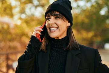 Young hispanic woman smiling happy talking on the smartphone at the park.