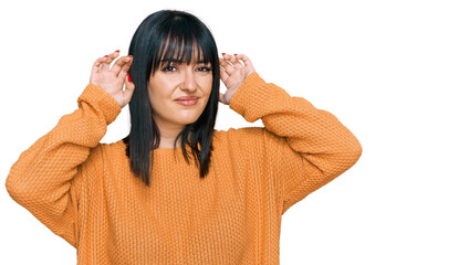 Young hispanic woman wearing casual clothes trying to hear both hands on ear gesture, curious for gossip. hearing problem, deaf