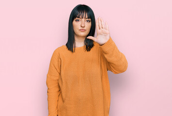 Young hispanic woman wearing casual clothes doing stop sing with palm of the hand. warning...