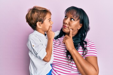 Hispanic family of mother and son hugging together with love serious face thinking about question...