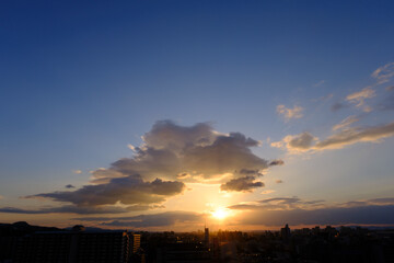 兵庫県神戸市東灘区の高層マンションの上層階からの夜明け。大阪生駒山から太陽が昇り、あたりはオレンジ色に染まり、ビル群がシルエットで浮かぶ。