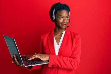 Young african american girl working at the office wearing operator headset smiling looking to the...