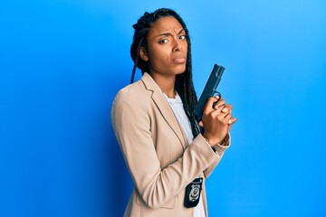African american police woman holding gun skeptic and nervous, frowning upset because of problem....
