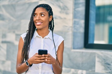 Young african american woman smiling happy using smartphone at the city.