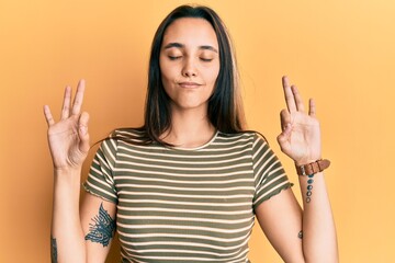 Young hispanic woman wearing casual striped t shirt relax and smiling with eyes closed doing meditation gesture with fingers. yoga concept.