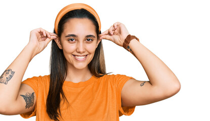 Young hispanic woman wearing casual clothes smiling pulling ears with fingers, funny gesture. audition problem
