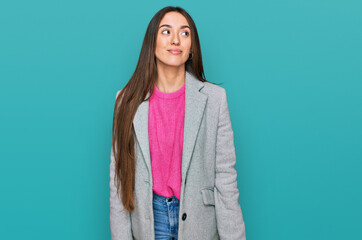 Young hispanic girl wearing business clothes smiling looking to the side and staring away thinking.