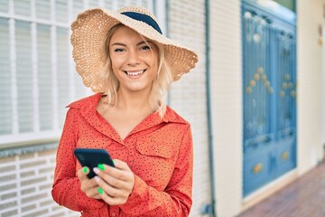 Young blonde tourist woman smiling happy using smartphone at the city.