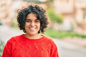 Young hispanic woman smiling happy looking to the camera at the city.