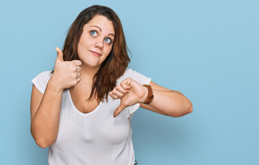 Young plus size woman wearing casual white t shirt doing thumbs up and down, disagreement and agreement expression. crazy conflict