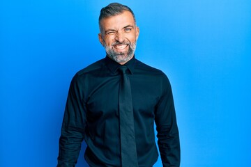 Middle age handsome man wearing business shirt and tie winking looking at the camera with sexy expression, cheerful and happy face.