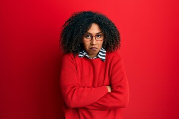 Fototapeta na wymiar Beautiful african american woman with afro hair wearing sweater and glasses skeptic and nervous, disapproving expression on face with crossed arms. negative person.