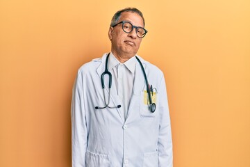 Middle age indian man wearing doctor coat and stethoscope depressed and worry for distress, crying angry and afraid. sad expression.