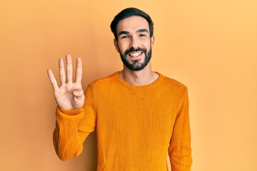 Young hispanic man wearing casual clothes showing and pointing up with fingers number four while smiling confident and happy.