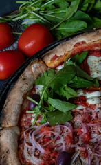 traditional Italian pizza with slices with arugula, sun dried tomatoes and ground pepperoni