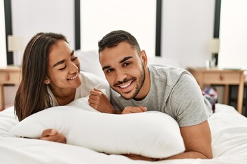 Young latin couple smiling happy hugging on the bed at home.